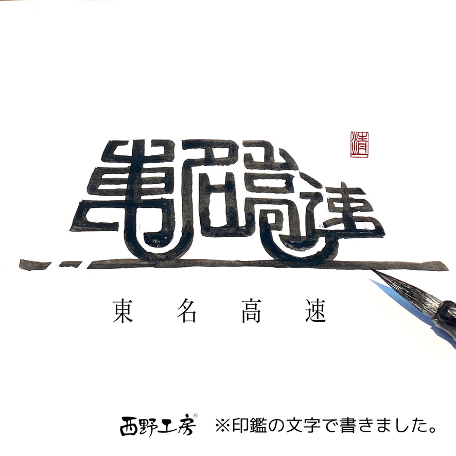 印鑑の文字で車の形をイメージして書いた「東名高速」の手書き作品。下に東・名・高・速の文字が並び、右下に筆先が写っている。