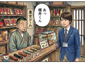 印鑑店の店内で、店主が来店したスーツ姿の男性を見て「あっ 櫻井くん」と驚く2コマ漫画風のイラスト。棚には印材が並び、「東京ドーム」「ハンコセット」などの文字が描かれている。嵐のライブ後の余韻を感じるような場面。