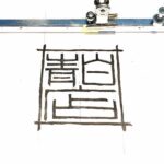 ローソンをイメージした青と白の看板を、印鑑職人が当て字で表現した創作印影デザイン。「青白店」の三文字を印章風に配置し、ローソンの日にちなんで制作したオリジナルはんこ案。